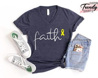 Könnte beinhalten: Ein marineblaues V-Ausschnitt-T-Shirt mit dem Wort "faith" in weißer Schrift und einem gelben Band.