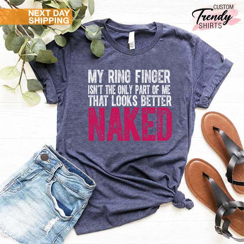 May include: A navy blue t-shirt with the text "MY RING FINGER ISN'T THE ONLY PART OF ME THAT LOOKS BETTER NAKED" in white and pink. The shirt is paired with denim shorts and brown sandals.