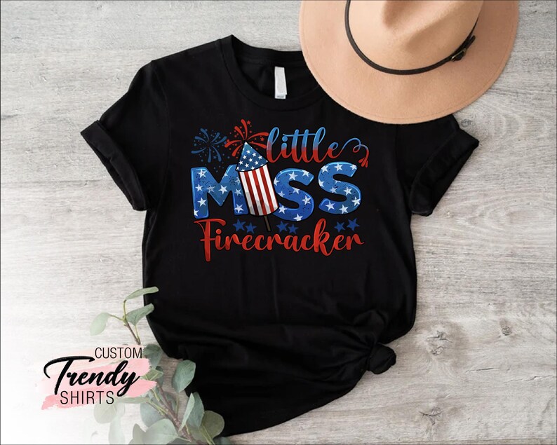 May include: Black t-shirt with a red, white, and blue firework graphic and the text "little miss firecracker".