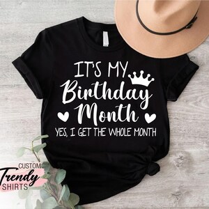 May include: Black t-shirt with white text that reads "It's My Birthday Month. Yes, I get the whole month."  A crown and two hearts are above the text.