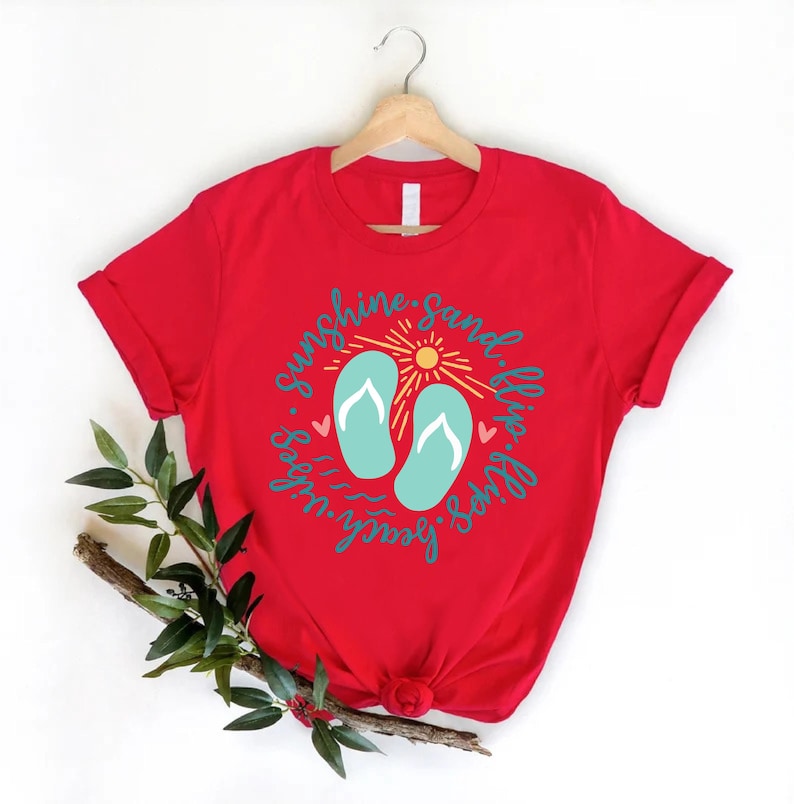 K&ouml;nnte beinhalten: Rotes T-Shirt mit einem Grafikdesign von Flip-Flops, einer Sonne und dem Text "Sunshine, Sand, Flip Flops, Beach Vibes".