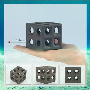 Puede incluir: Decoración de acuario en forma de cubo gris oscuro con múltiples aberturas circulares. El cubo, de aproximadamente 1,5 cm, se sostiene en una mano. Se muestran vistas adicionales del cubo debajo de la imagen principal.