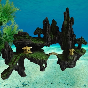 Puede incluir: Decoración de acuario con un paisaje de isla en miniatura. La formación rocosa negra tiene musgo verde y pequeños árboles. También se incluyen dos pagodas doradas en miniatura y un puente. El fondo es una escena submarina azul.