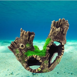 Puede incluir: Adorno decorativo para acuario con forma de tocón de árbol desgastado. La estructura de resina marrón y beige presenta múltiples aberturas y está adornada con parches de musgo verde vibrante, creando una escena submarina natural.