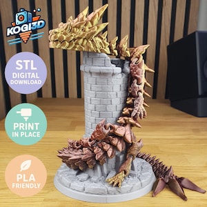 Op de afbeelding: Een 3D-geprinte drakenfiguur in goud- en bruintinten, bovenop een grijze bakstenen toren. De gedetailleerde schubben en klauwen van de draak zijn zichtbaar. De tekst "KOGI3D", "STL DIGITAL DOWNLOAD", "PRINT IN PLACE" en "PLA FRIENDLY" is inbegrepen.