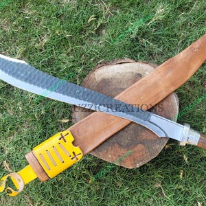 May include: A silver and brown-handled knife with a curved blade and a leather sheath. The sheath is yellow with a brown leather strap and has a decorative stitching pattern.