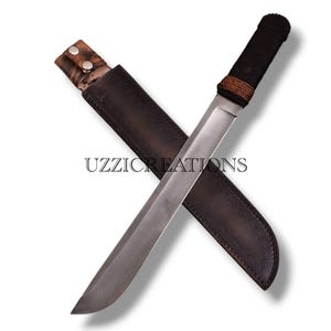 May include: A large, silver knife with a black and brown handle, in a dark brown leather sheath. The image includes the text "UZZICREATIONS".