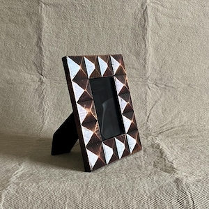 Może przedstawiać: Biały ceramiczny kubek z czarnym uchwytem i napisem "But First, Coffee" pogrubioną, czarną czcionką. Kubek jest ustawiony na rozmytym tle, podkreślając jego czysty design.