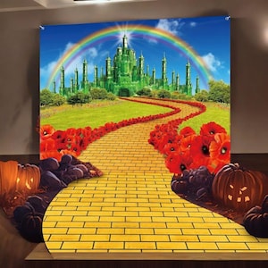 May include: A backdrop featuring a vibrant scene from The Wizard of Oz. The image showcases a yellow brick road leading to a green Emerald City under a rainbow. Red poppies line the path, with carved pumpkins and dark purple grapes in the foreground.