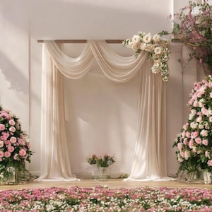 May include: A wedding ceremony backdrop featuring a draped fabric archway, adorned with floral arrangements. The arch is draped with flowing, cream-colored fabric. Pink and white flowers are arranged on the floor and in vases, creating a romantic setting.