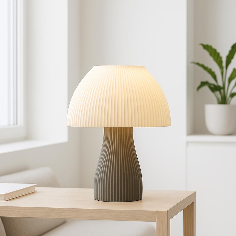 May include: A gray ceramic table lamp with a white pleated lampshade. The lamp is shaped like a mushroom and has a textured base.