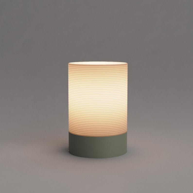 Puede incluir: Una l&aacute;mpara de mesa blanca con una pantalla de vidrio acanalada y una base verde.