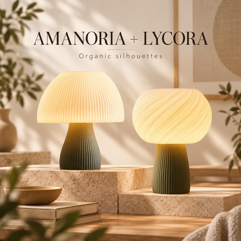 Op de afbeelding: Twee paddestoelvormige tafellampen met het opschrift AMANORIA + LYCORA Organic silhouettes. De linkerlamp heeft een cr&egrave;mekleurige geplooide kap en een donkergroene voet. De rechterlamp heeft een wervelende cr&egrave;mekleurige kap.