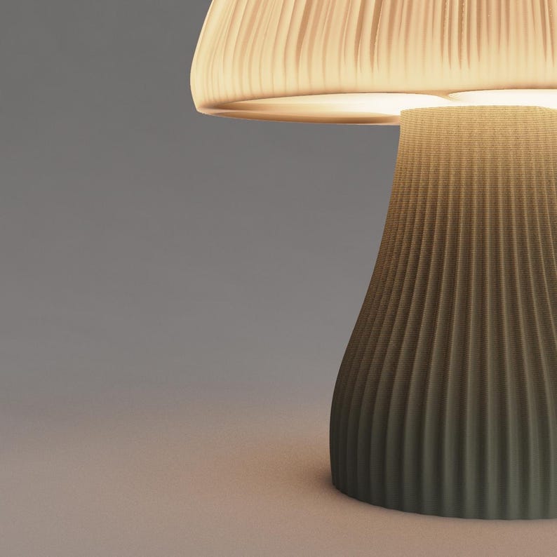 May include: A mushroom-shaped table lamp with a pleated, off-white shade and a textured, dark green base.