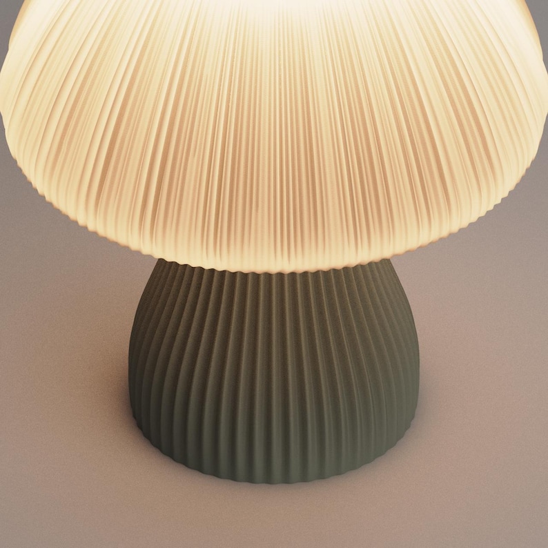 May include: A mushroom-shaped table lamp with a white pleated shade and a green ribbed base.