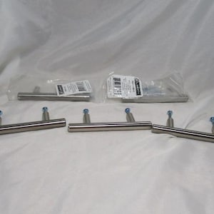 May include: A collection of stainless steel cabinet pulls with blue accents. Some pulls are packaged, while others are loose. The pulls have a T-bar design and are suitable for drawers or cabinets.