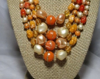 A 1950's set of Orange, Cream and Peach Simulated Pearls and Art Glass Four Strand Necklace & Matching Earrings.