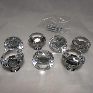 May include: Set of six clear crystal cabinet knobs with faceted surfaces and chrome-colored bases. Includes a small bag of screws. These decorative knobs add a touch of elegance to furniture.