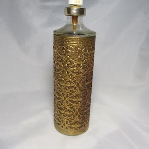 May include: A vintage perfume bottle with a gold filigree design. The bottle has a clear glass top and a white and gold atomizer. The gold filigree wraps around the clear glass bottle. The bottle is approximately 6 inches tall.