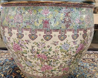 May include: Large, ornate ceramic planter with a wide, rounded shape. The planter features a detailed floral design in shades of pink, blue, and green against a cream background. The rim has a decorative border, and the overall style is reminiscent of antique Asian pottery.