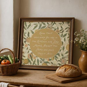 Könnte beinhalten: Ein gerahmtes quadratisches Wandbild mit einem senfgelben Kreis und dem Text: Know that even when you are in the kitchen, our Lord moves amidst the pots and pans. Teresa of Avila. Der Hintergrund zeigt ein botanisches Muster aus Blättern und Früchten.