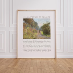 May include: Framed art print featuring a landscape painting with a path and trees. The text "ALL CREATURES OF OUR GOD" is at the top, with additional text below the image. The frame is a light brown color.