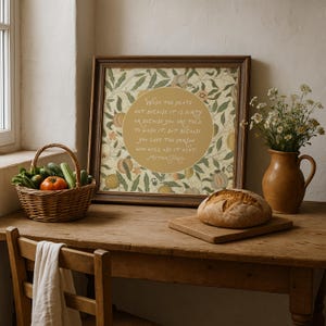 Puede incluir: Una impresión de arte mural enmarcada con un patrón botánico de hojas y frutas, con un círculo dorado central que contiene el texto: Wash the plate not because it is dirty or because you are told to wash it, but because you love the person who will use it next. Mother Teresa.