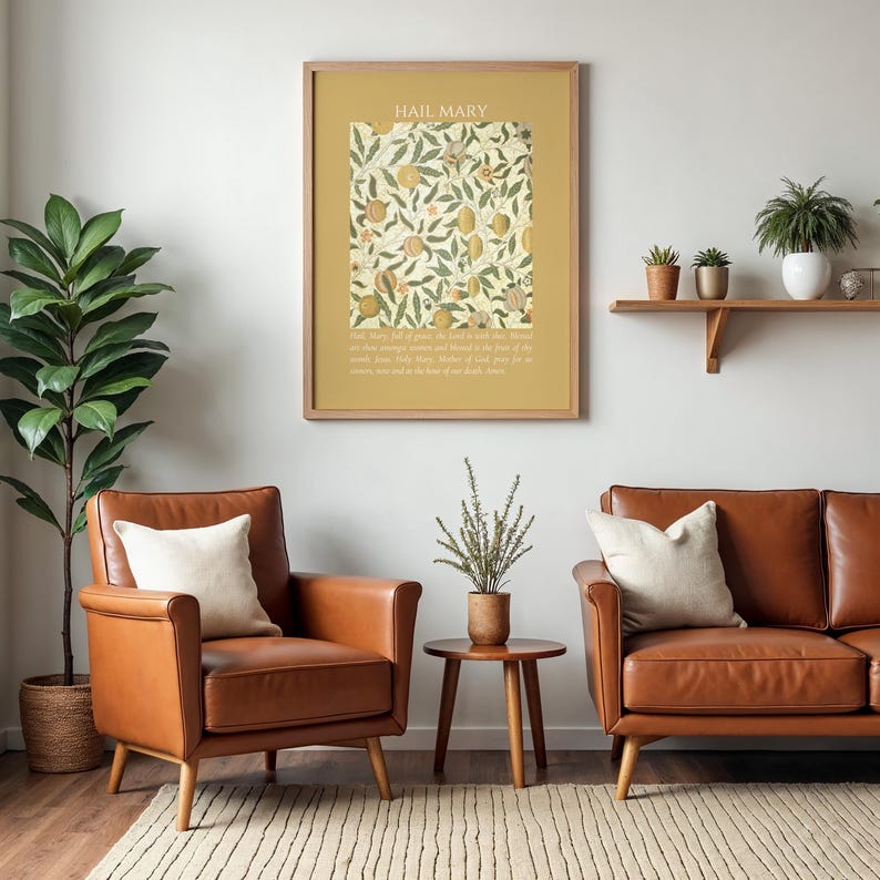 May include: A framed wall art print featuring the text HAIL MARY at the top, a central square illustration of botanical fruit and leaf patterns in muted tones, and a prayer text at the bottom, all set against a solid mustard yellow background.