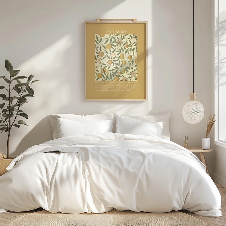 May include: A framed vertical wall art print titled HAIL MARY featuring a botanical pattern of green leaves and yellow fruit on a mustard yellow background, displayed above a bed with white bedding and pillows in a bright, neutral-toned room.