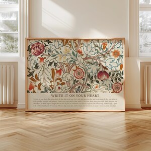 May include: A framed art print featuring a floral design with red, orange, and cream colors. The artwork includes the text "WRITE IT ON YOUR HEART" at the bottom. The print is displayed in a room with natural light.