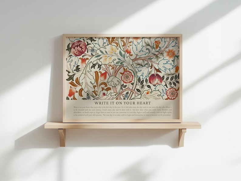 May include: A framed floral art print with a beige background and a wooden frame. The print features a colorful botanical design with red, orange, and green flowers and leaves. The text "WRITE IT ON YOUR HEART" is at the bottom.
