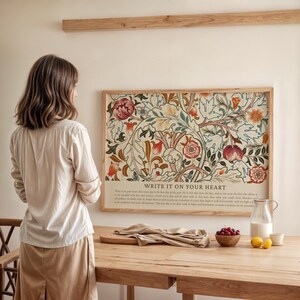 May include: A framed floral art print with a wooden frame. The print features a detailed botanical design in shades of red, orange, green, and cream. The text "WRITE IT ON YOUR HEART" is at the bottom. The print is displayed on a wall.