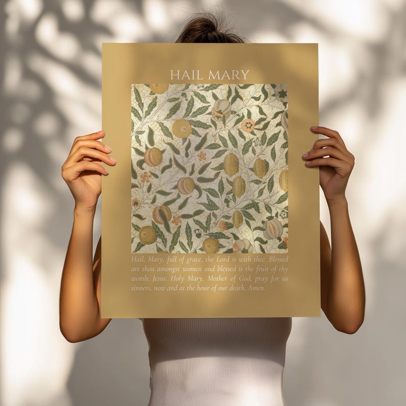 May include: A rectangular poster with a mustard yellow border featuring the text HAIL MARY at the top. The center displays a botanical pattern of green leaves, vines, and orange fruits. The bottom includes the full Hail Mary prayer in white text.