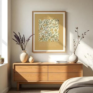 May include: A framed wall art print featuring a mustard yellow background with the text HAIL MARY at the top and the prayer text at the bottom. The center displays a rectangular botanical illustration of oranges, leaves, and flowers in muted tones.