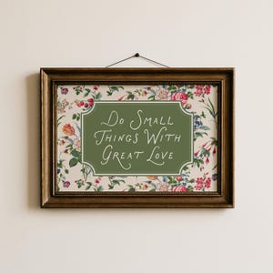 Puede incluir: Un cuadro enmarcado con el mensaje "Do Small Things With Great Love". La impresión tiene un fondo floral y un centro verde. El marco es de madera oscura y ornamentada.