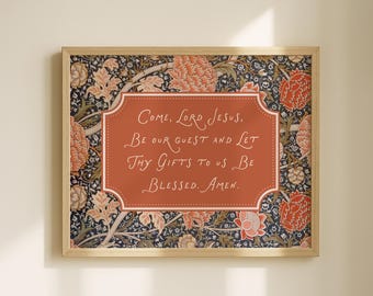 May include: A rectangular framed wall art piece featuring a central terracotta-colored plaque with white cursive text that reads: Come, Lord Jesus, Be our guest and let Thy gifts to us be blessed. Amen. The background displays a floral pattern.
