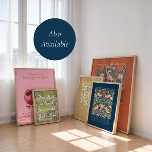May include: Five framed art prints leaning against a wall. The prints feature various designs including a pink poster with a pomegranate, a green floral print with text, a yellow botanical print, and two dark blue and orange floral patterned posters.