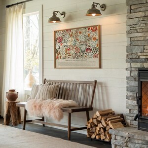 May include: A cozy living room scene featuring a wooden bench with striped pillows and a pink fur throw. A framed floral print hangs above the bench, with the text "WRITE IT ON YOUR HEART". The room has a fireplace and a stack of firewood.