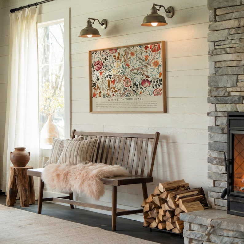 May include: A cozy living room scene featuring a wooden bench with striped pillows and a pink fur throw. A framed floral print hangs above the bench, with the text "WRITE IT ON YOUR HEART". The room has a fireplace and a stack of firewood.