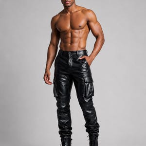 May include: Black leather cargo pants with multiple pockets and a straight leg fit. The pants are paired with black lace-up boots. The model is standing in front of a gray background.