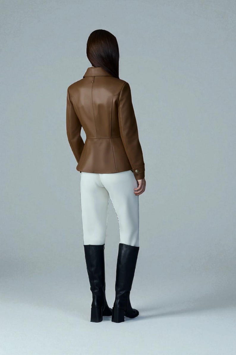 May include: A brown leather jacket with a tailored fit, featuring a collar and button details. Paired with white pants and black knee-high boots. The jacket's color is a rich, warm brown.