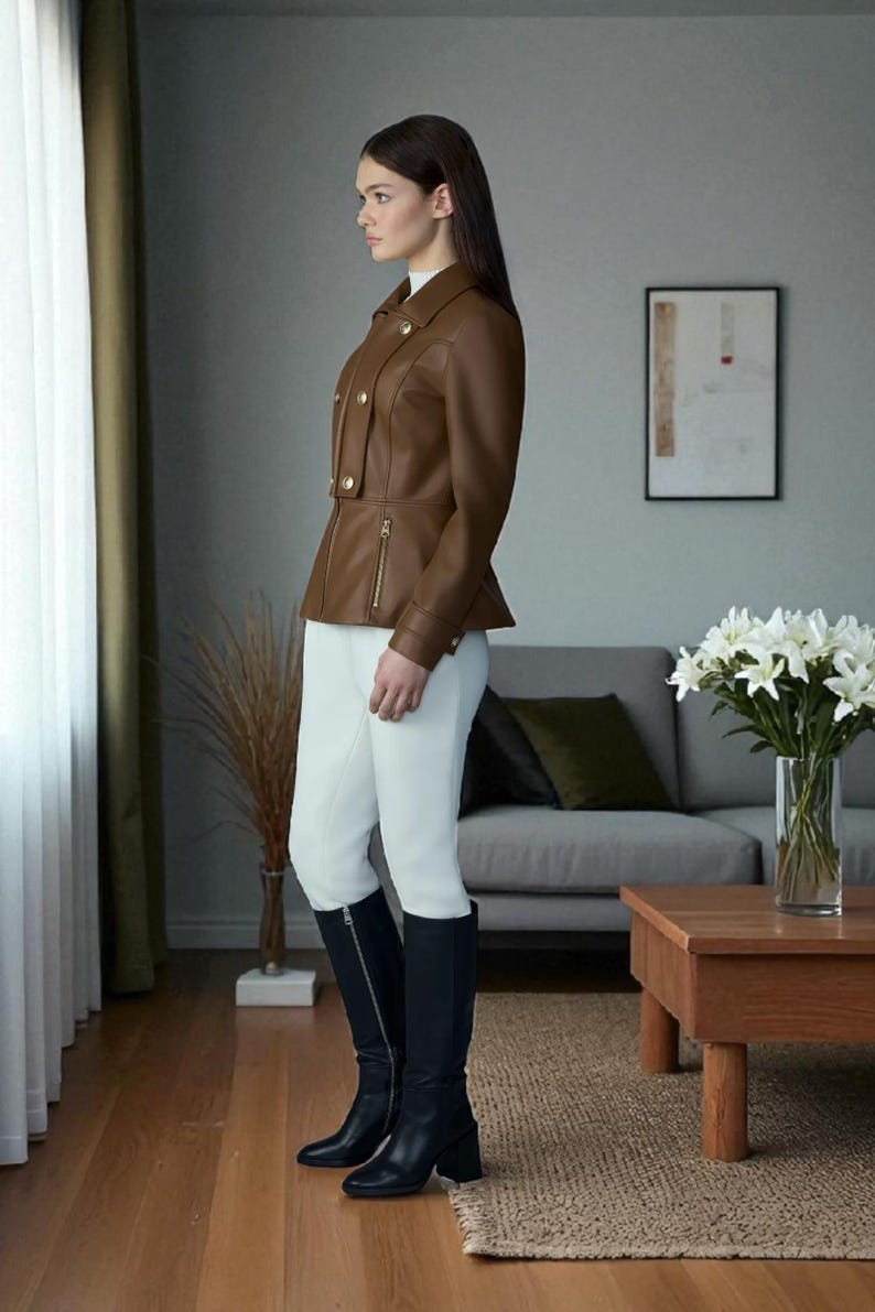 May include: A brown leather jacket with gold buttons and a zipper, paired with white pants and black knee-high boots. The jacket has a tailored fit. The boots have a block heel. The outfit is suitable for equestrian or formal wear.