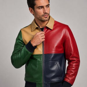 May include: A color-block leather jacket in red, navy, green, and tan. The jacket has a collared neckline, a front zipper, and a ribbed knit hem and cuffs. The jacket features a single pocket on the front.