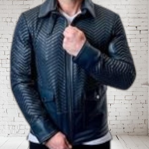 May include: A navy blue leather jacket with a chevron pattern. The jacket has a collared neckline, a zipper closure, and two front pockets. The sleeves have a textured design. The person is wearing a white shirt underneath.