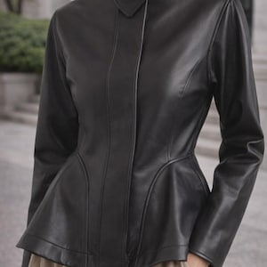 May include: A black leather jacket featuring a high collar and a peplum waist. The jacket has long sleeves and a tailored fit. The design includes vertical seams and a button closure. A stylish outerwear garment.
