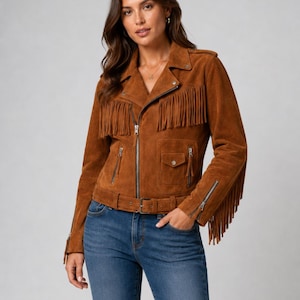 May include: A brown suede motorcycle jacket featuring long fringe detailing on the chest and sleeves, a notched lapel, a silver-toned asymmetrical front zipper, zippered pockets, a flap pocket, and a buckled belt at the waist.
