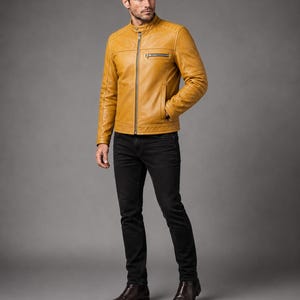 May include: A mustard yellow leather jacket with a stand-up collar, a full-length front zipper, and a zippered chest pocket. The jacket features quilted shoulder detailing and long sleeves, paired with slim-fit black denim jeans and dark brown boots.