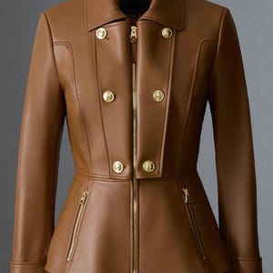 May include: A brown leather jacket with a tailored fit, featuring a double-breasted design with gold-colored buttons and a front zipper. The jacket has a peplum waist and two zippered pockets. The collar is a classic notched style.