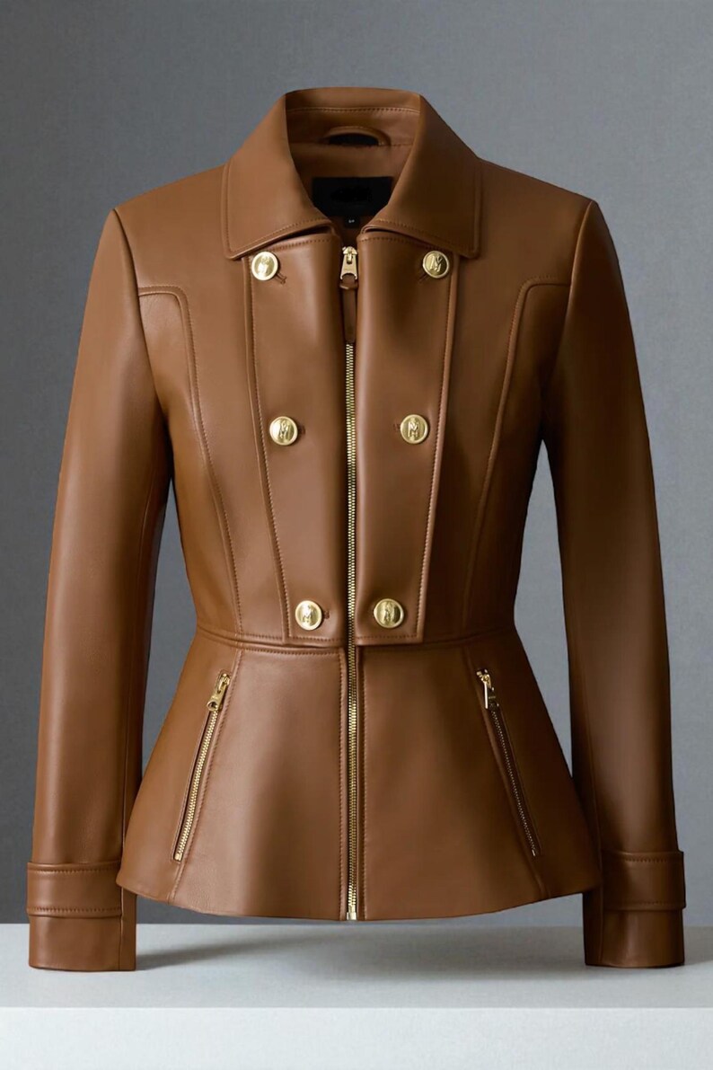 May include: A brown leather jacket with a tailored fit, featuring a double-breasted design with gold-colored buttons and a front zipper. The jacket has a peplum waist and two zippered pockets. The collar is a classic notched style.