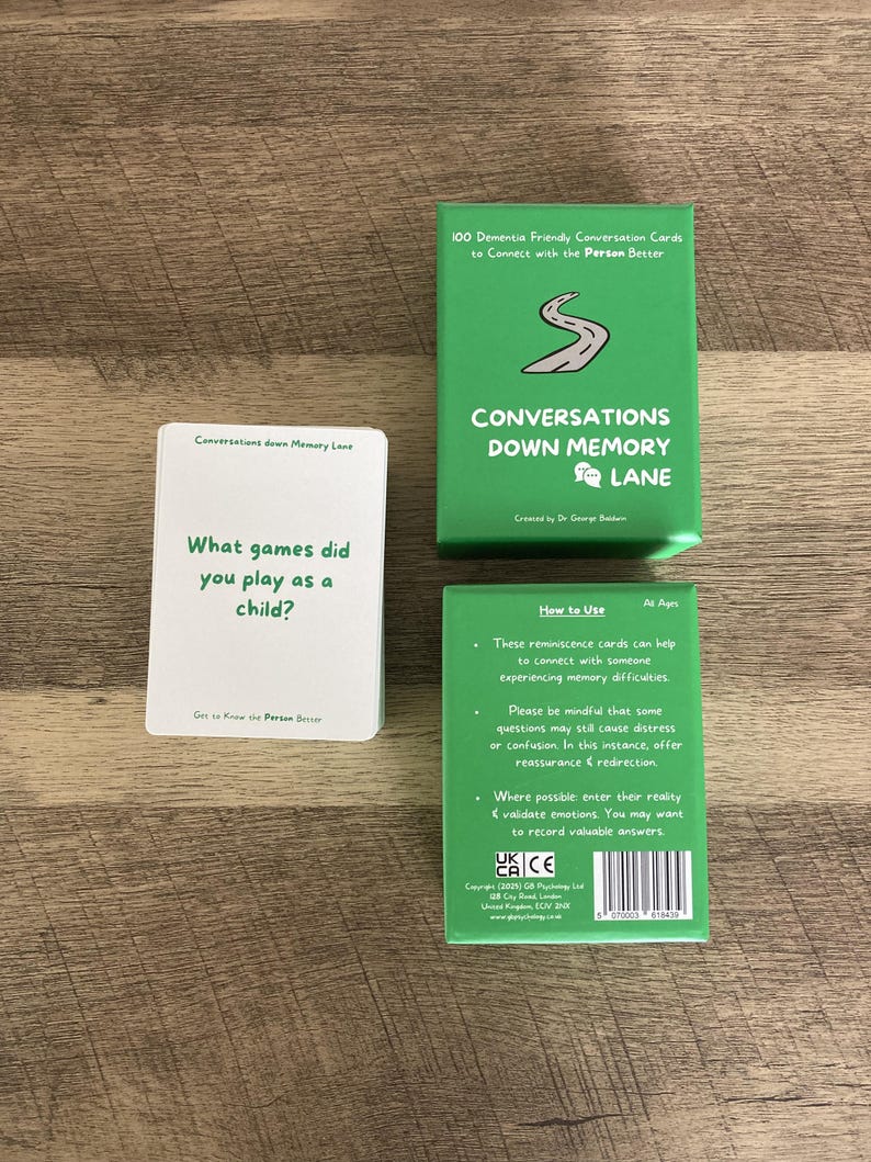 May include: A set of dementia-friendly conversation cards. The green box reads "Conversations Down Memory Lane." One card asks, "What games did you play as a child?" The cards are designed to connect with people experiencing memory difficulties.